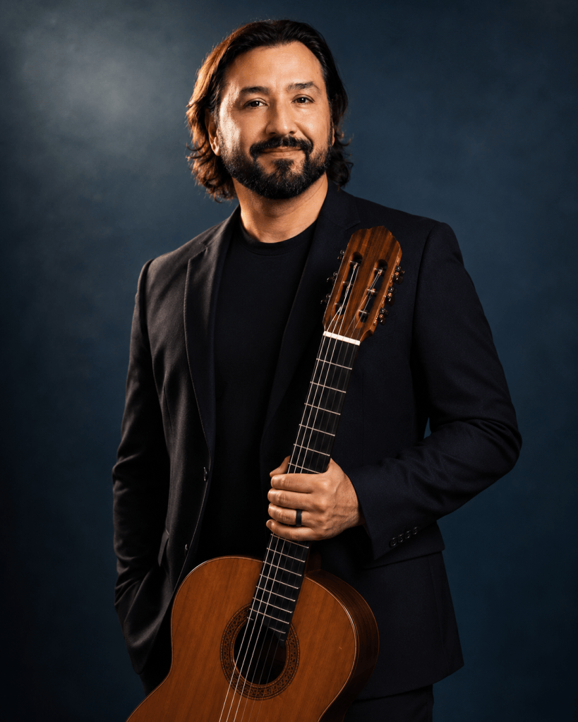 Jesus Palominos holding a classical guitar.